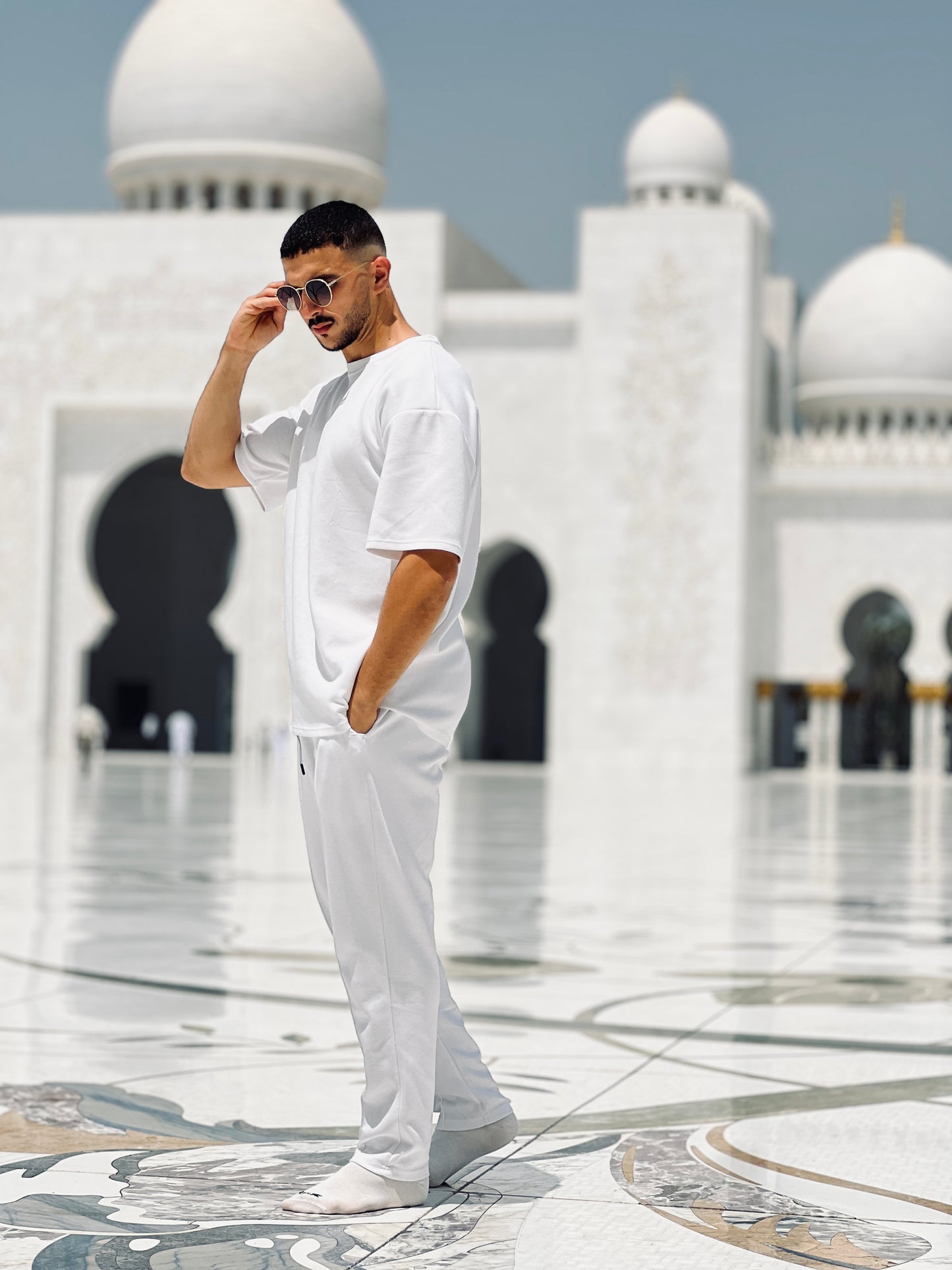 model in a white outfit standing in front of cheikh zayed mosque wearing xxxl